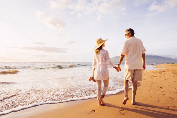 49643698 - happy romantic middle aged couple enjoying beautiful sunset walk on the beach. travel vacation retirement lifestyle concept