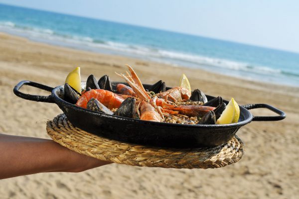 32139727 - a typical spanish paella with seafood in a paellera, the paella pan, on the beach